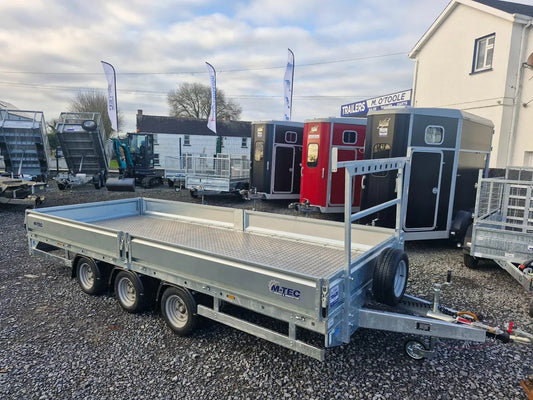 Metal trailer with 'M-Tec' branding on a gravel surface with other trailers in the background.